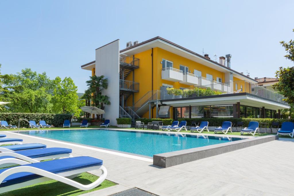 uma piscina com espreguiçadeiras e um edifício em Hotel Campagnola em Riva del Garda
