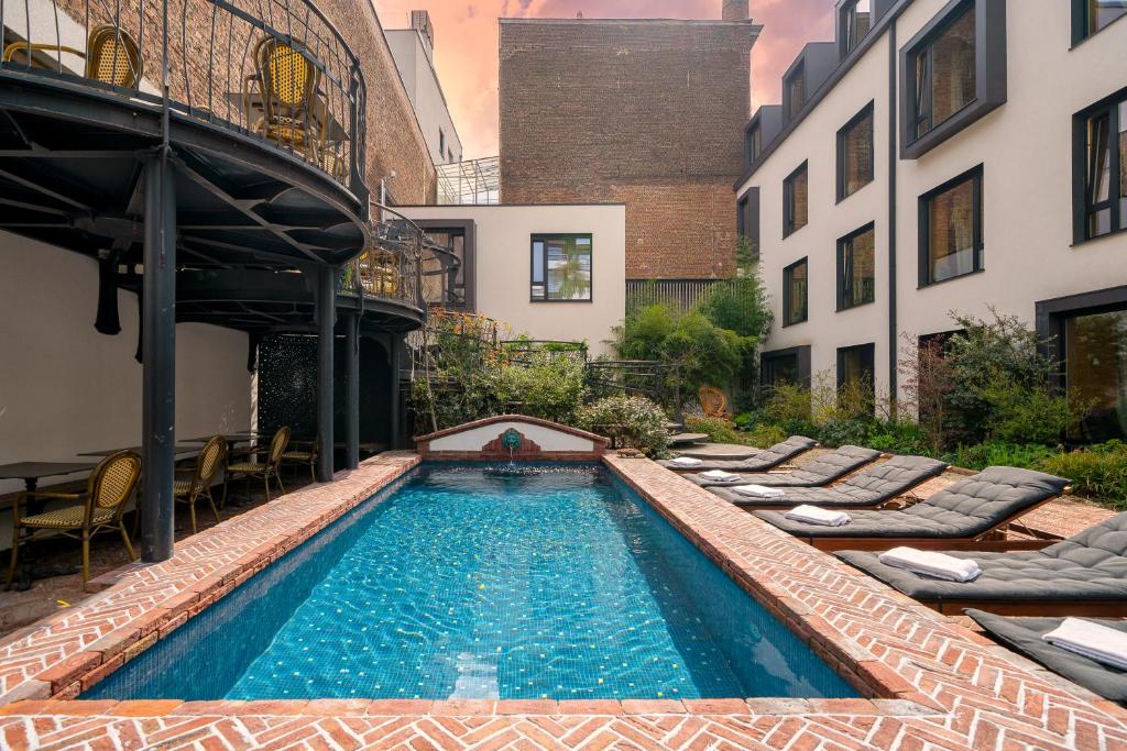 a swimming pool with chaise lounge chairs next to a building at Jardin Secret in Brussels