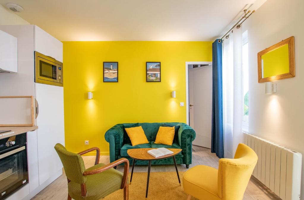 - un salon jaune avec un canapé vert et des chaises dans l'établissement Chez Emile Le Jaune Vendée - T2 renové - Terrasse, à Niort