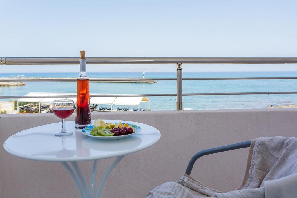 a table with a glass of wine and a plate of food at Sole Mare Seaside Apartments in Gouves