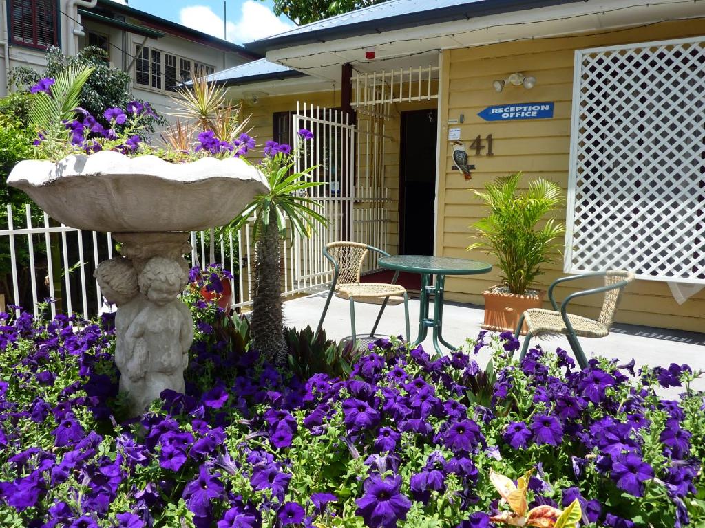 un jardín con flores púrpuras y una fuente en Kookaburra Inn, en Brisbane