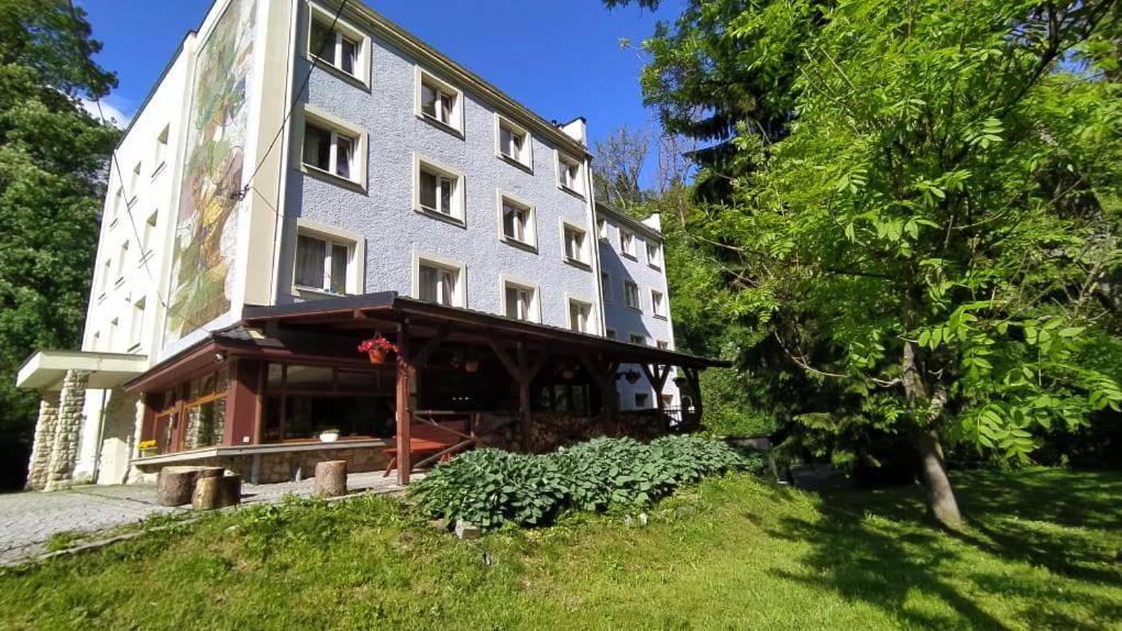 a large white building on a grassy hill at Pensjonat 4 Pory roku in Duszniki Zdrój