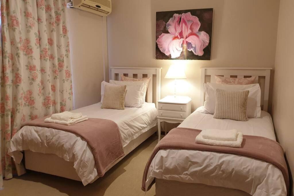 a bedroom with two beds and a flower painting on the wall at Coral Tree House in Graaff-Reinet