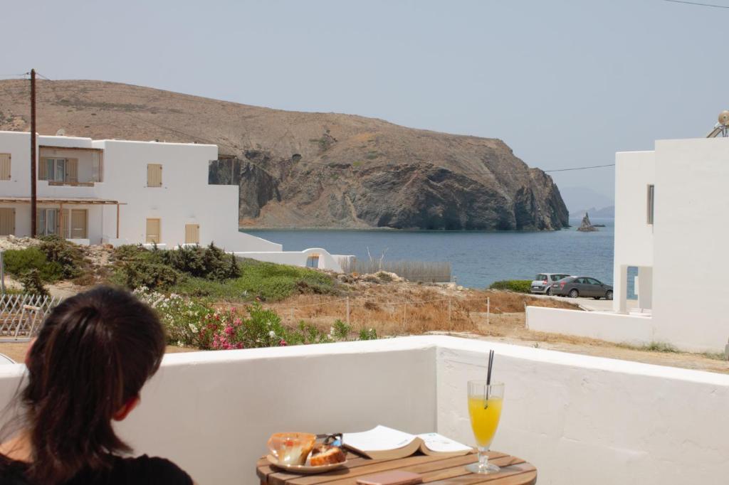 波洛尼亞的住宿－V-rooms in Milos Cyclades，坐在桌子上看着大海的女人