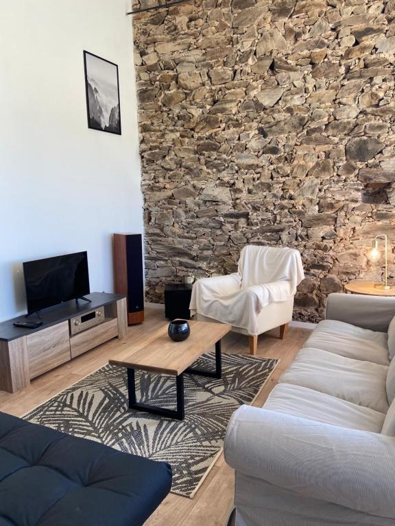 a living room with a stone wall at « La Crécerelle » spacieux gîte contemporain entre Tarn et Aveyron in Sainte-Gemme