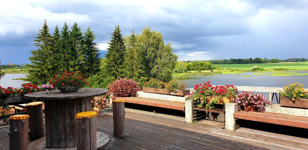 a wooden deck with flowers and a table and a lake at Ilmatsalu Motell in Ilmatsalu