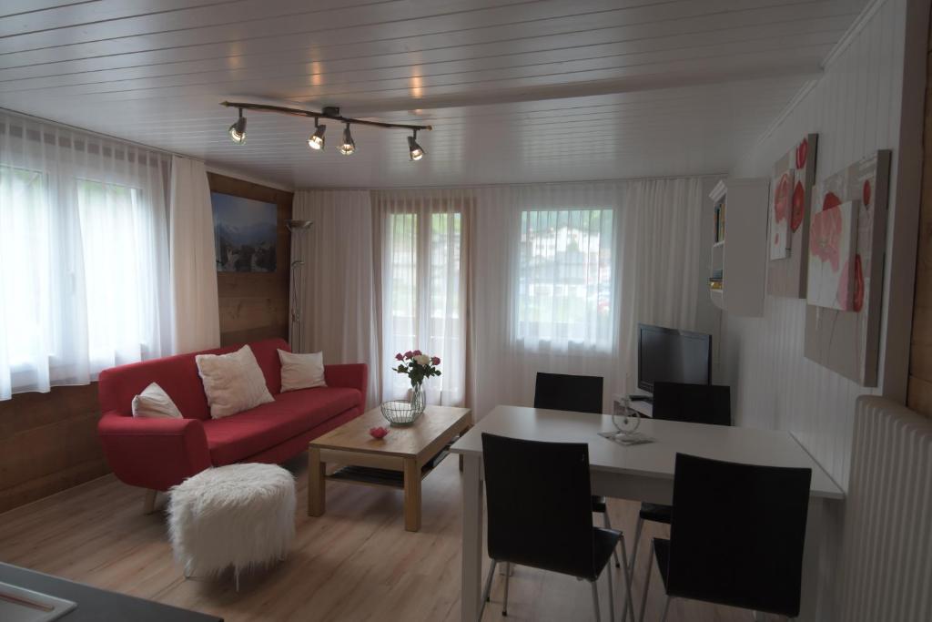 a living room with a red couch and a table at Haus Wiedersehen, Weissmies (3-Zi) in Saas-Grund