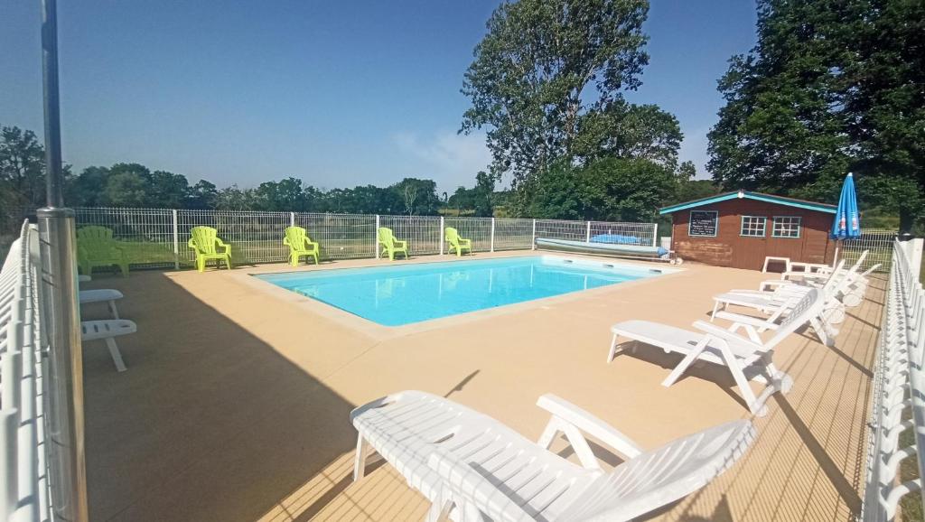 a swimming pool with white chairs and a swimming poolvisor at Camping des Papillons in Lalizolle