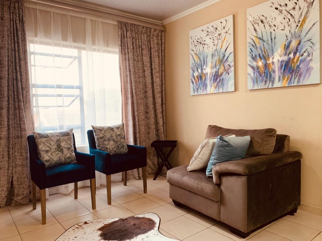 a living room with a couch and chairs and a window at Tshamani self catering in Hazyview