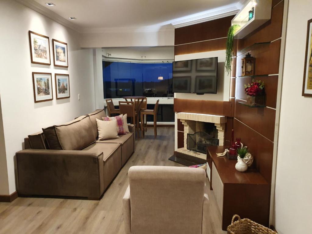sala de estar con sofá y chimenea en Temporada Gramado e Canela- Apartamento Centro Canela Boulevard, en Canela