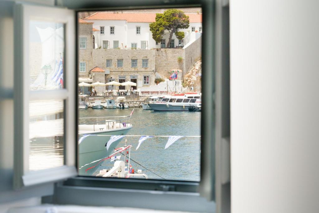een raam met uitzicht op een jachthaven met boten in het water bij MyCrown Suite, Luxurious apartment with sea view located at the port of Hydra in Hydra