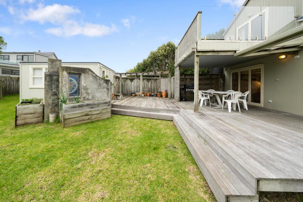 a backyard with a wooden deck with a table and chairs at Stroll to the Sea - Te Horo Beach Holiday House in Te Horo