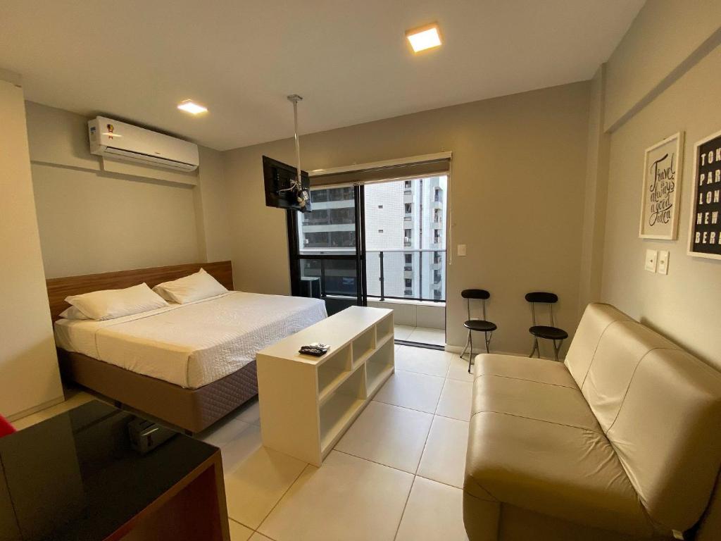 um quarto com uma cama, um sofá e uma janela em Edifício Time Apto 623 ER Hospedagens em Maceió