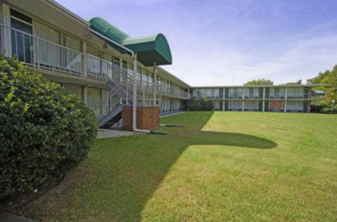 a large building with a grass yard in front of it at Express Airport Inn in Sandston