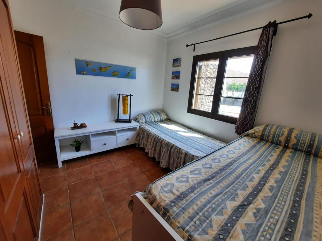 1 dormitorio con 2 camas y ventana en Lanzate en Tinajo