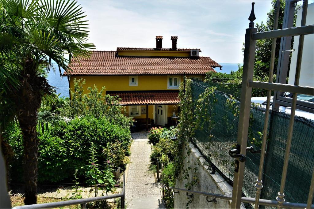 una casa amarilla con una valla delante de ella en Apartments and Rooms Vila Irma, en Opatija