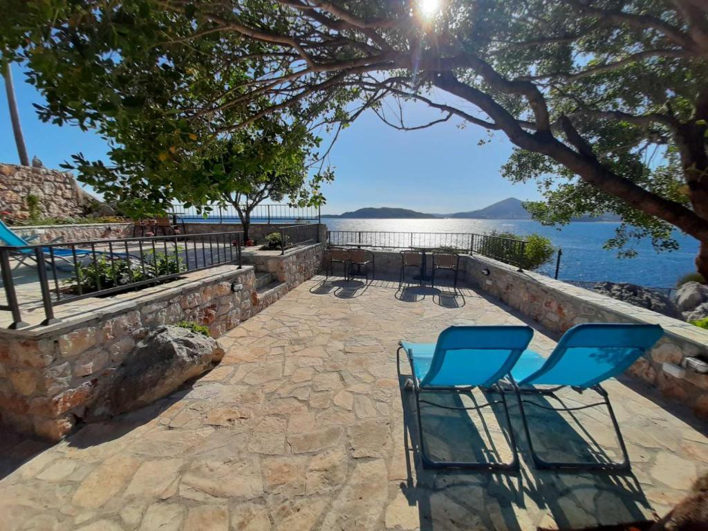 a pair of chairs sitting on a stone walkway next to the water at Apartments Mitrovići Miločer in Sveti Stefan