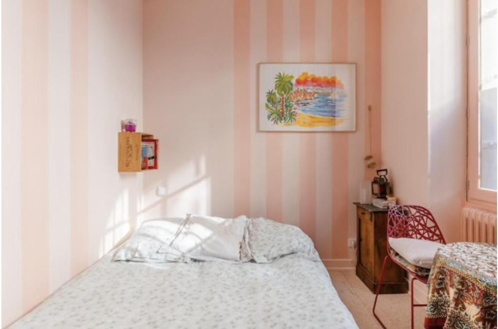 um quarto com uma cama e uma cadeira em Charmante chambre double chez l'habitant em Pantin