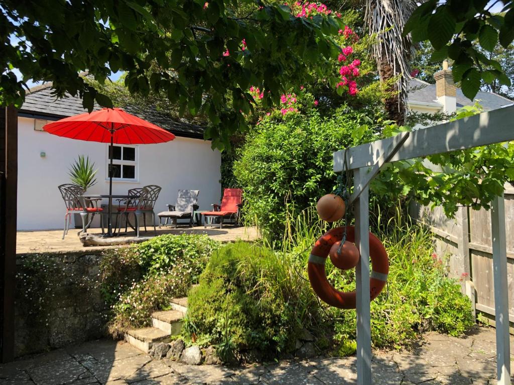 une terrasse avec un parasol rouge, une table et des chaises dans l'établissement Little Gem with Private Hot Tub - Up to 25 percent off ferry, à Shanklin