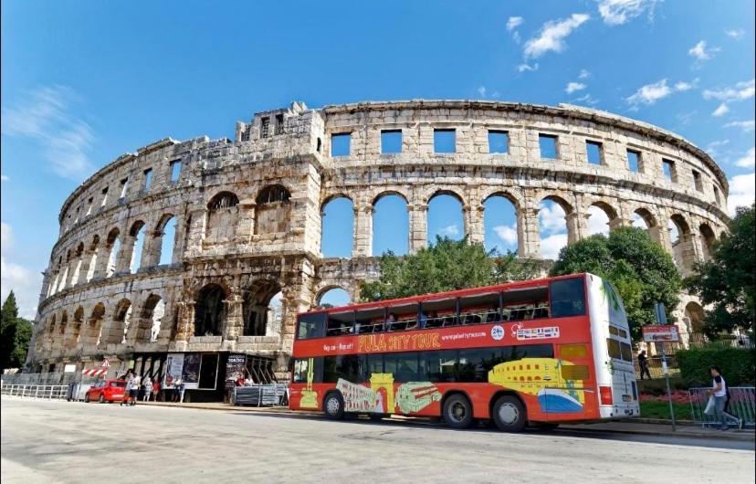 a red double decker bus in front of the coliseum at Two Room Eva in Pula