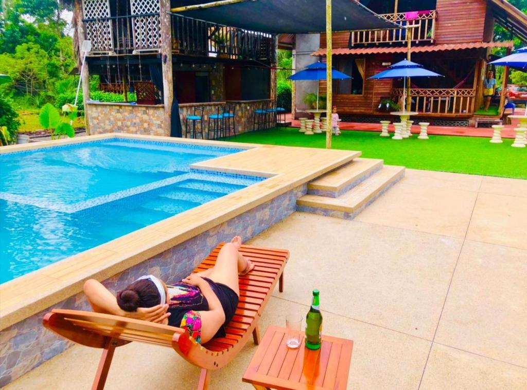 a woman laying on a chair next to a swimming pool at QUINTA PRIMAVERA - Hostería Campestre in Nueva Loja