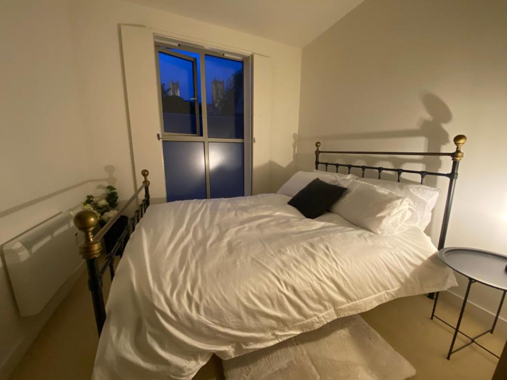 a bedroom with a bed with white sheets and a window at Central, modern and peaceful, lovely Cathedral views, two-bed apartment with 40" smart TV & free onsite parking in Lincoln