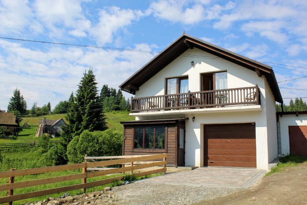 ein weißes Haus mit einem Balkon und einem Zaun in der Unterkunft Уютный котедж "Hatynka" in Jablunyzja