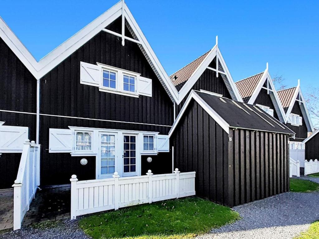 Czarny dom z białym płotem przed nim w obiekcie 6 person holiday home in Nyk bing Sj w mieście Rørvig