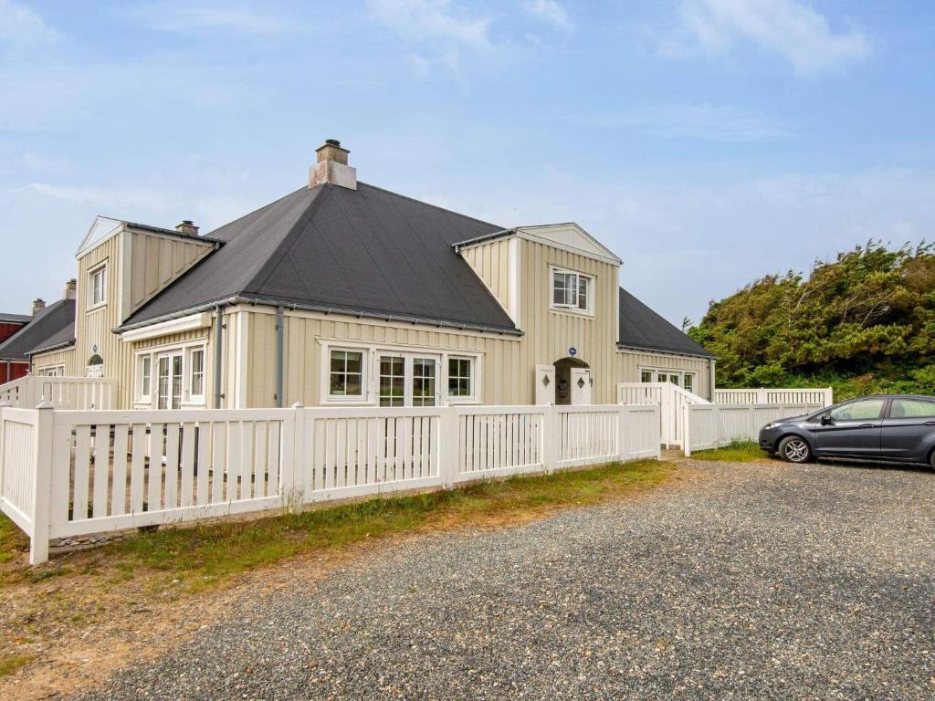 una casa grande con una valla blanca y un coche en 4 person holiday home in Ringk bing, en Ringkøbing