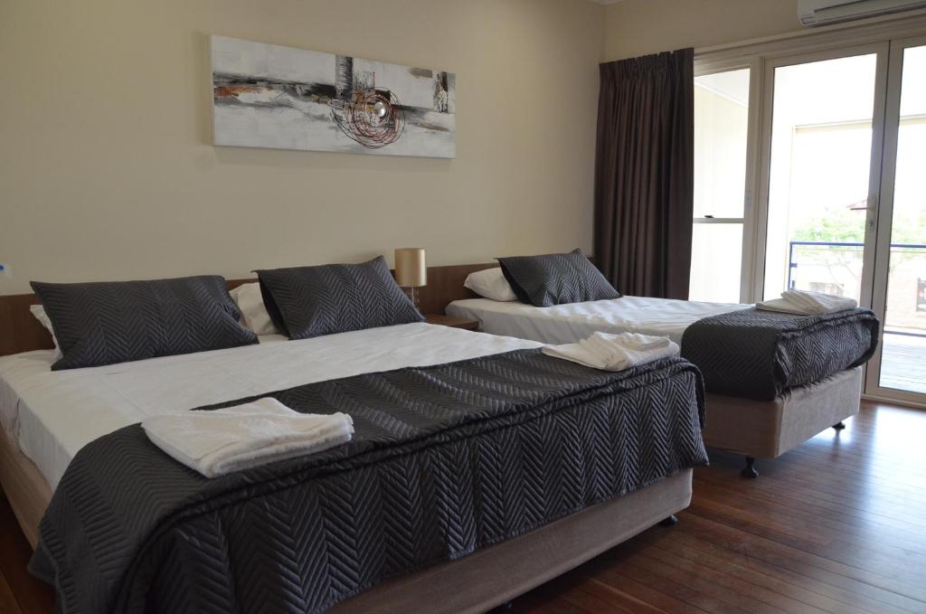 two beds in a room with a window at The Australian Hotel Motel in Dalby