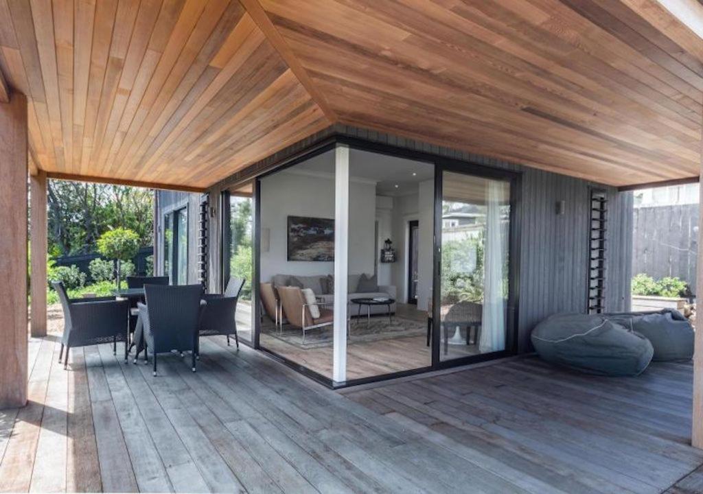 a patio with a wooden roof and a dining room at Moa 30 Runga - Waiheke Island in Oneroa