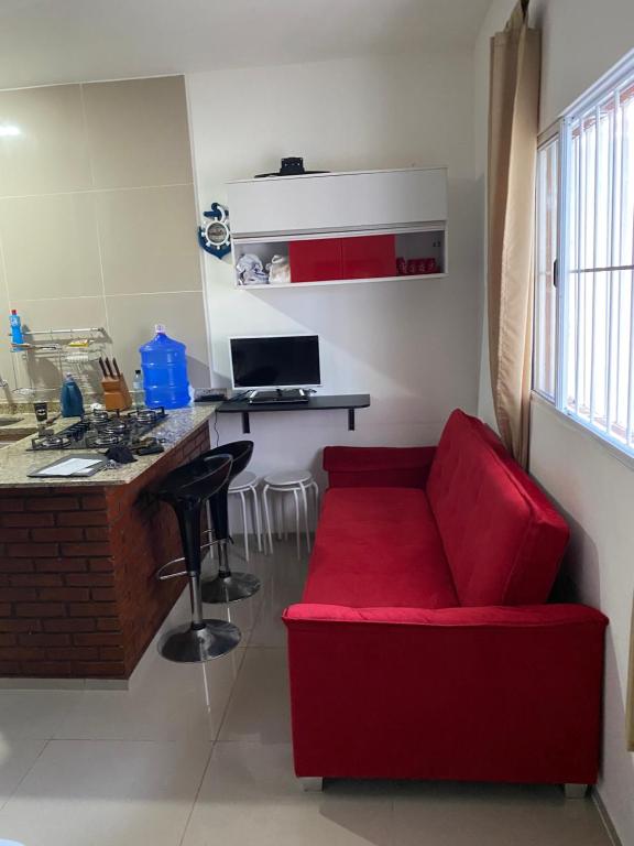 een rode bank in een keuken met een bureau bij Apartamento aconchegante in Ubatuba