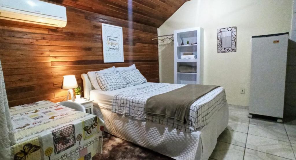 1 dormitorio con 2 camas y pared de madera en Chalé suíte com ar em Resende, en Resende