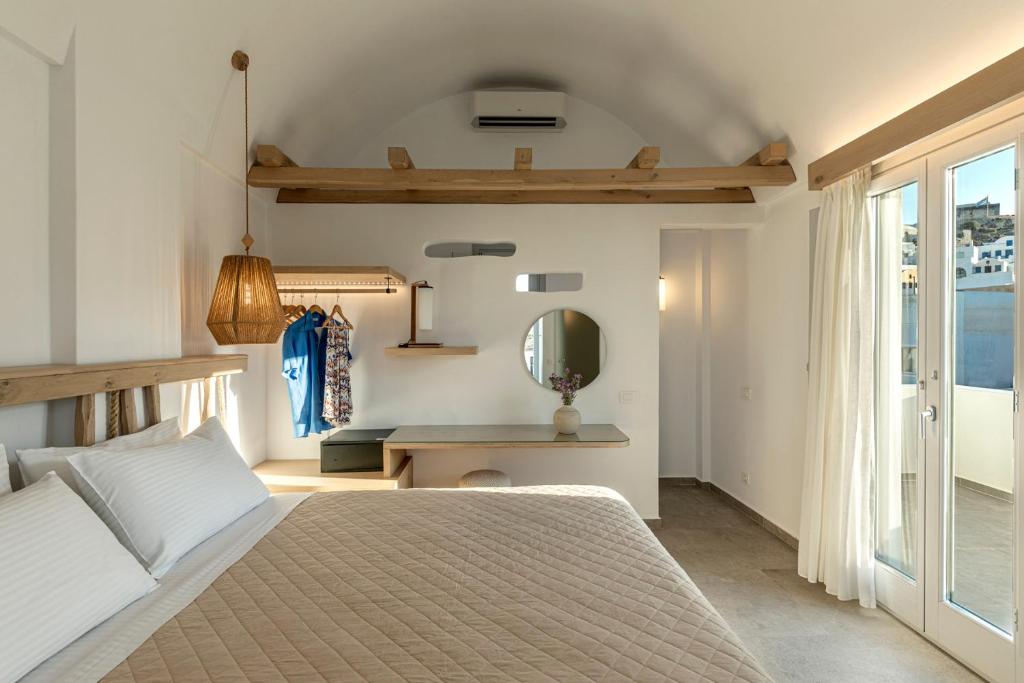 Un dormitorio con una cama y un escritorio con espejo. en Alafropetra Luxury Suites, en Akrotiri
