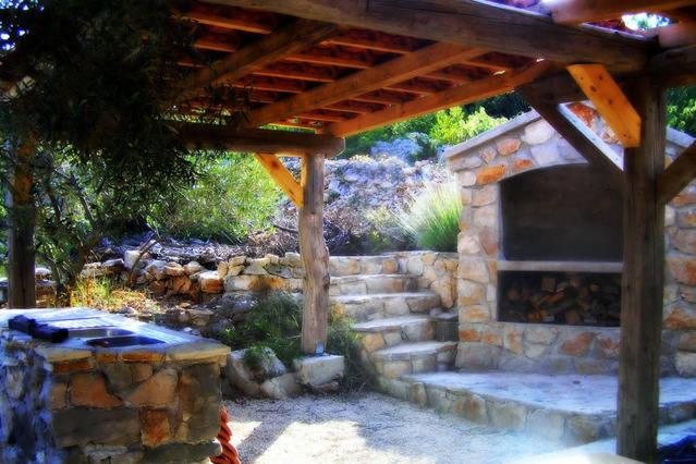 a stone fireplace sitting under a wooden roof at Miniature house for two in Jezera