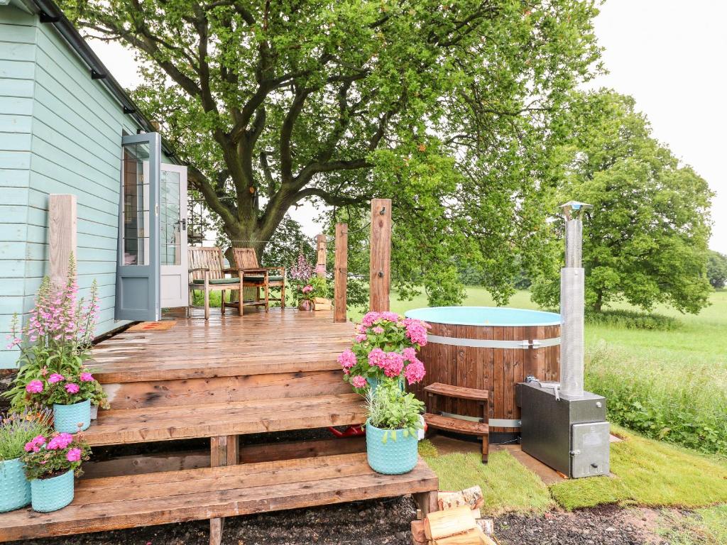 a wooden deck with a hot tub and flowers at The Lazy Mare by The Water in Rugeley