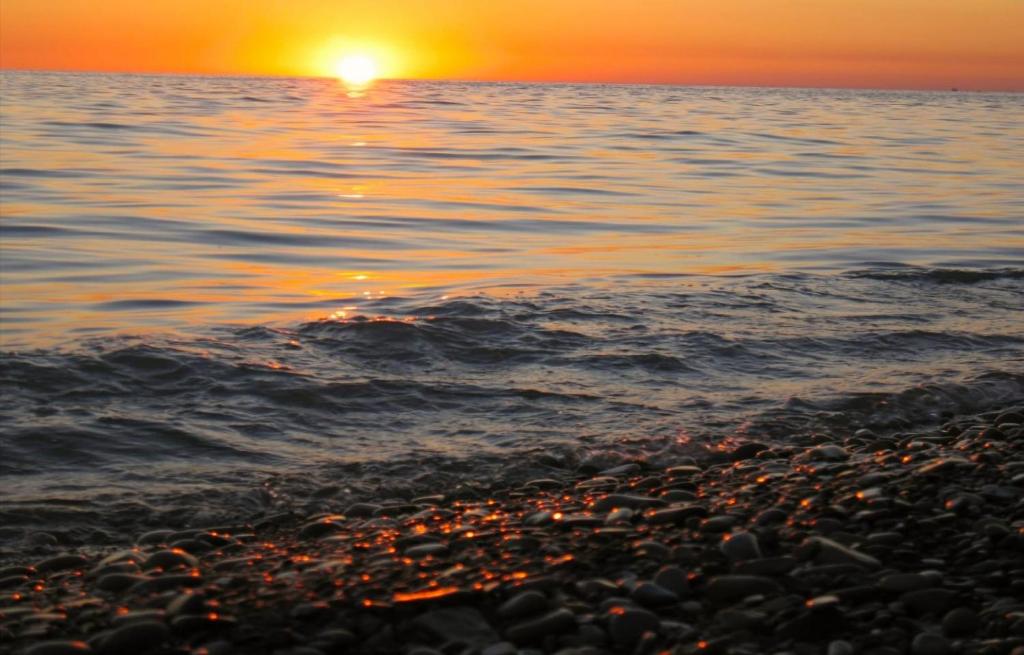 a sunset over the water with a rocky beach at Lora Studio in Mamaia Nord