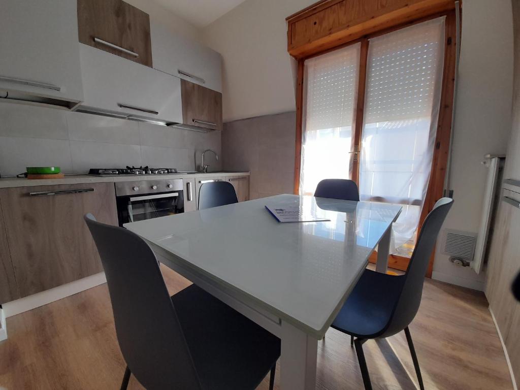 uma cozinha com uma mesa branca com cadeiras e uma janela em Casa Stella Marina em Bellaria-Igea Marina