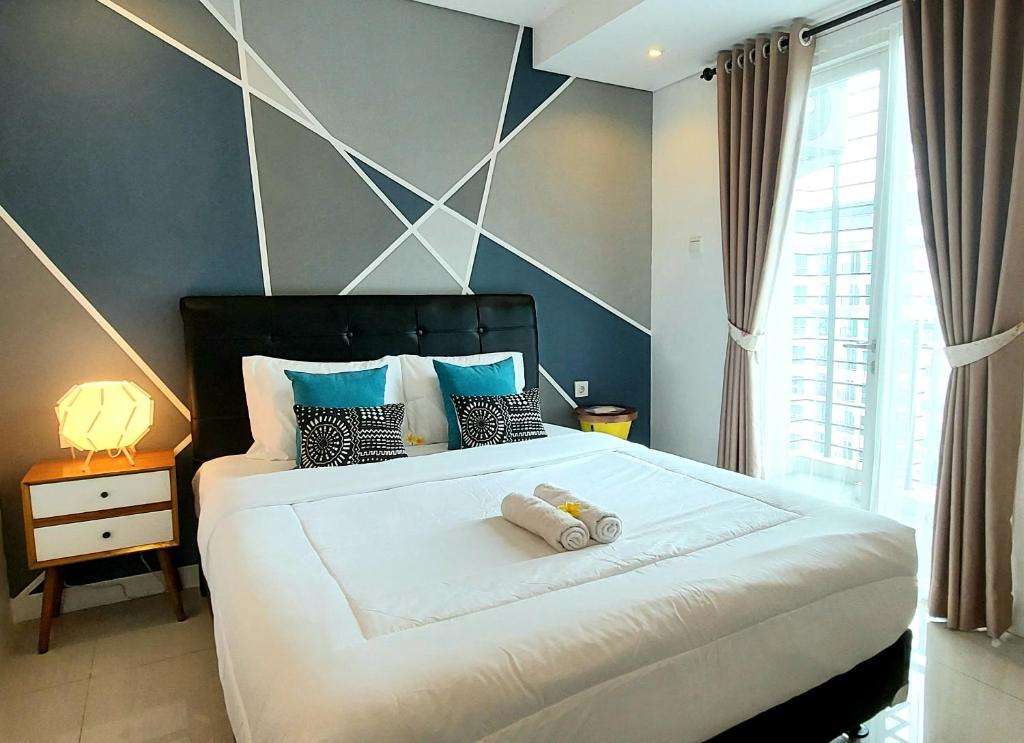 a bedroom with a large white bed with blue walls at Woodland Park Residence-Relaxed and Friendly in Jakarta