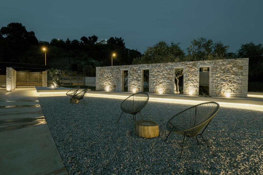 three chairs sitting in front of a stone building at Casa Costa Suites in Kanali