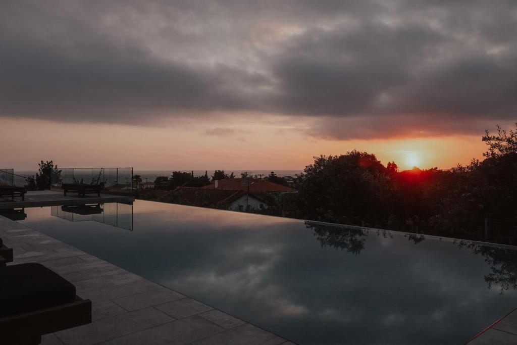 a sunset over a swimming pool with the sun setting at Casa Costa Suites in Kanali