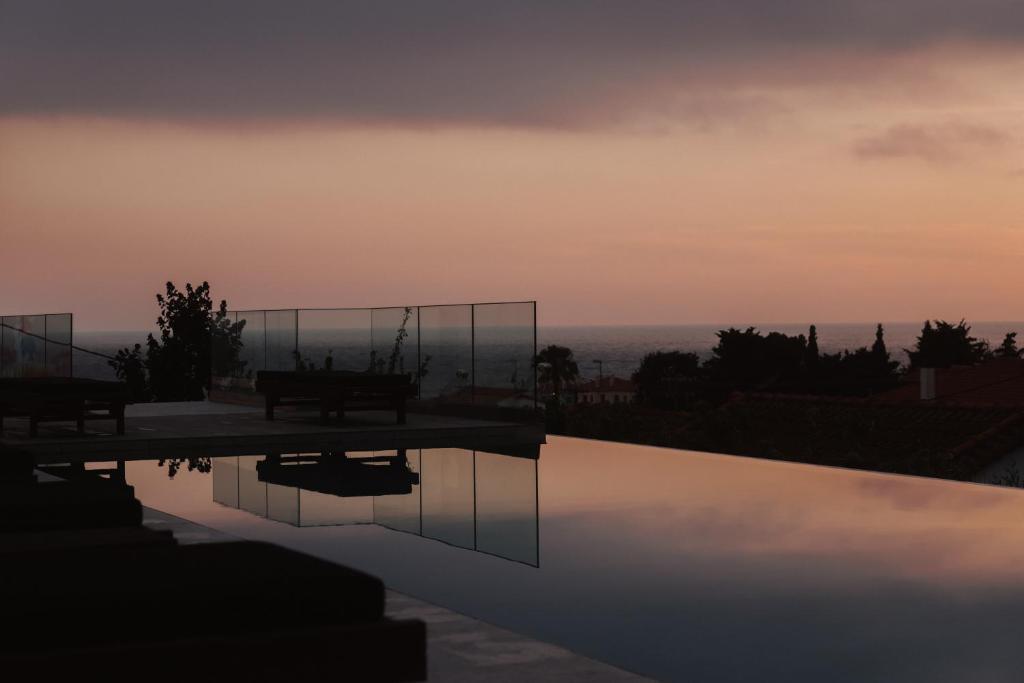 a swimming pool with a sunset in the background at Casa Costa Suites in Kanali