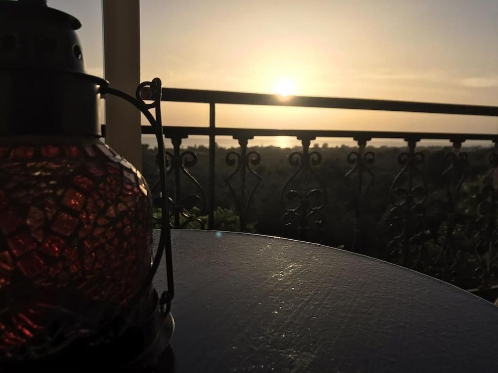 a table with a vase on a balcony with the sunset at Beautiful Farm House in Filiatra