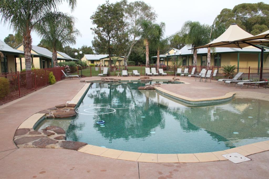 a swimming pool in a yard with chairs around it at Murray River Resort in Moama