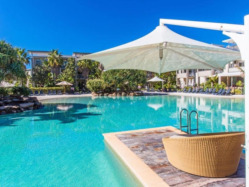 a swimming pool with a chair and an umbrella at Resort and Spa 2306-7 in Kingscliff