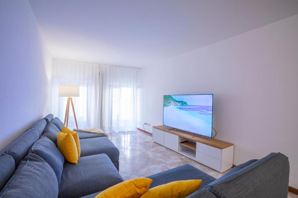 een woonkamer met een blauwe bank en een flatscreen-tv bij Cozy Apartment In The Heart Of Riva in Riva del Garda