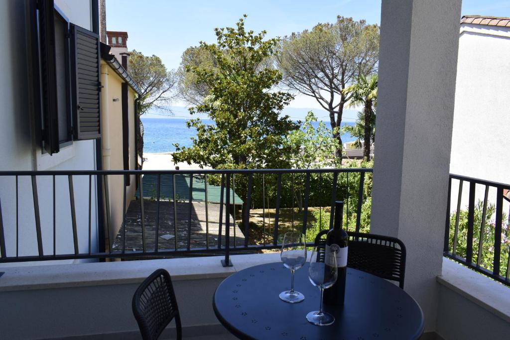 a table with wine glasses on a balcony with the ocean at Apartments Grey, Green i White in Malinska