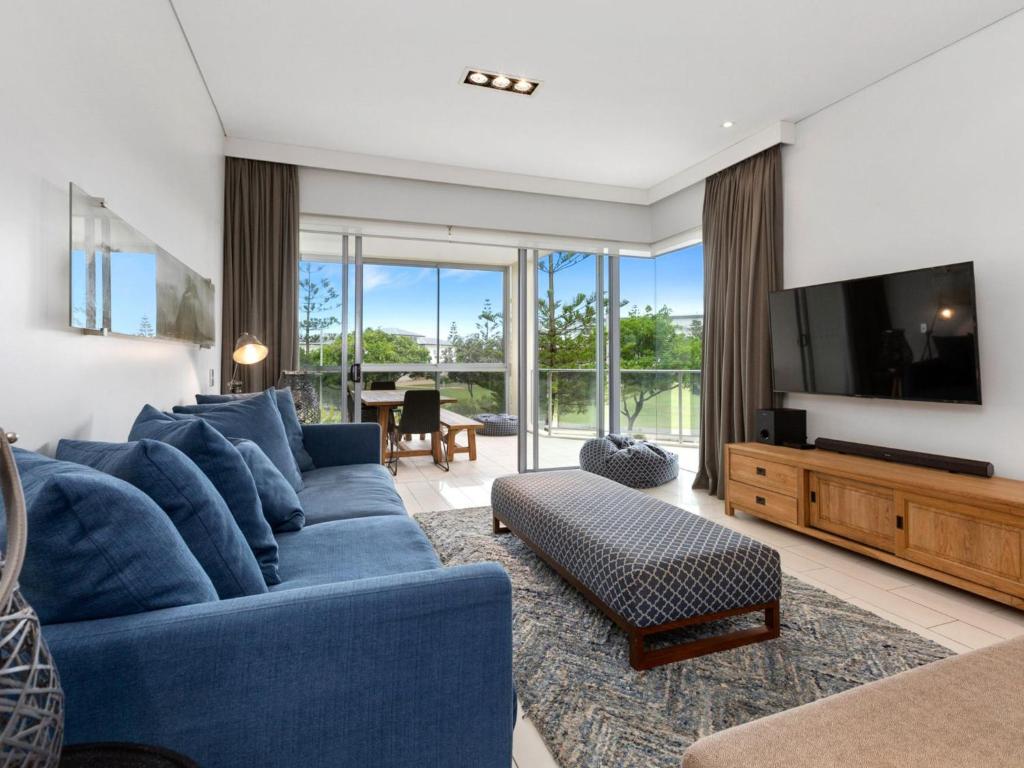 uma sala de estar com um sofá azul e uma televisão em Sea Culture 1110 Apartment with complex Pool & Spa em Kingscliff