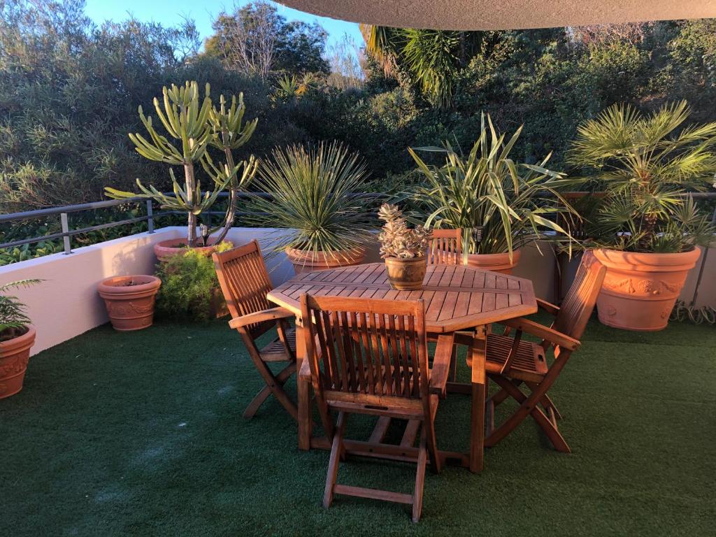 une table et des chaises en bois sur une terrasse ornée de plantes dans l'établissement Bel appartement au calme vue imprenable parking privé gratuit, à La Ciotat