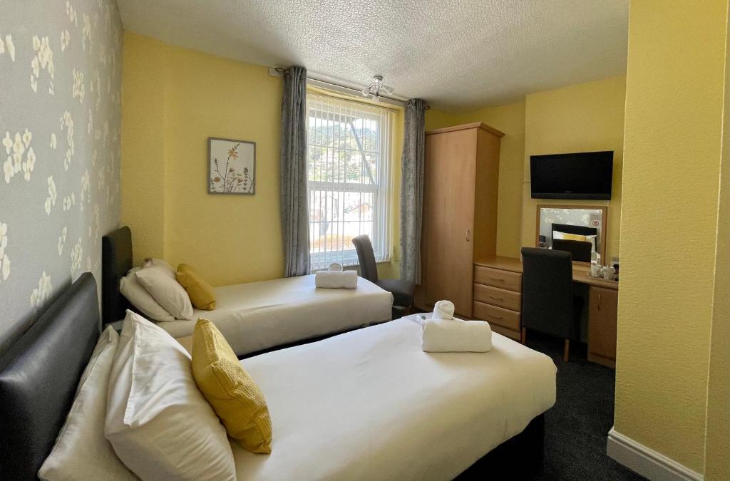 a hotel room with two beds and a desk at Milverton House in Llandudno